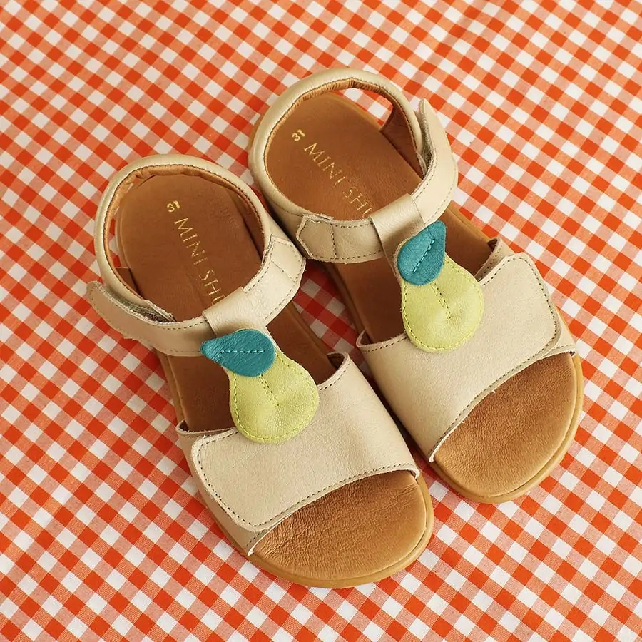 Sandalia infantil Origen en color beige con detalle decorativo de pera, diseño ergonómico.
