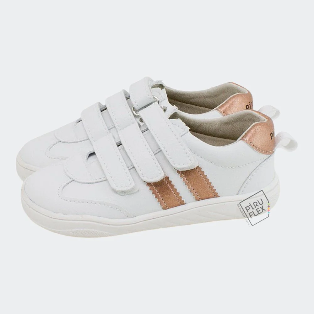 Deportivo vegano de Piruflex en color blanco con detalles en rosa metalizado, triple cierre de velcro y diseño moderno y cómodo para niños.