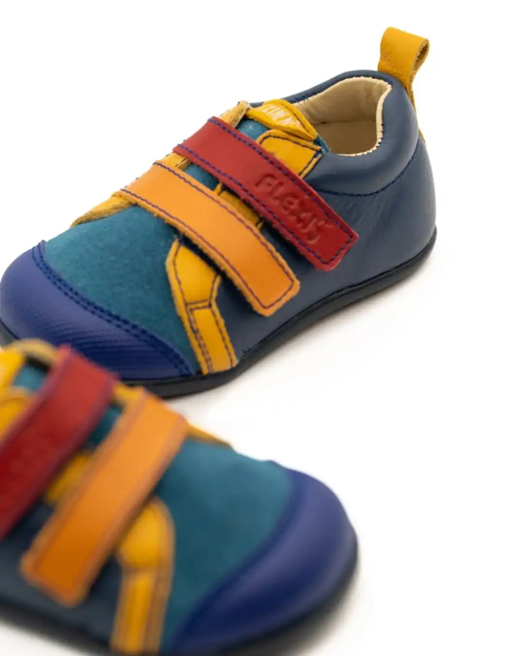 Deportiva infantil modelo 152 de Flexinens, con suela Hilda azul y detalles en colores rojo, naranja y amarillo. Diseño respetuoso y ergonómico para los pies de los niños.