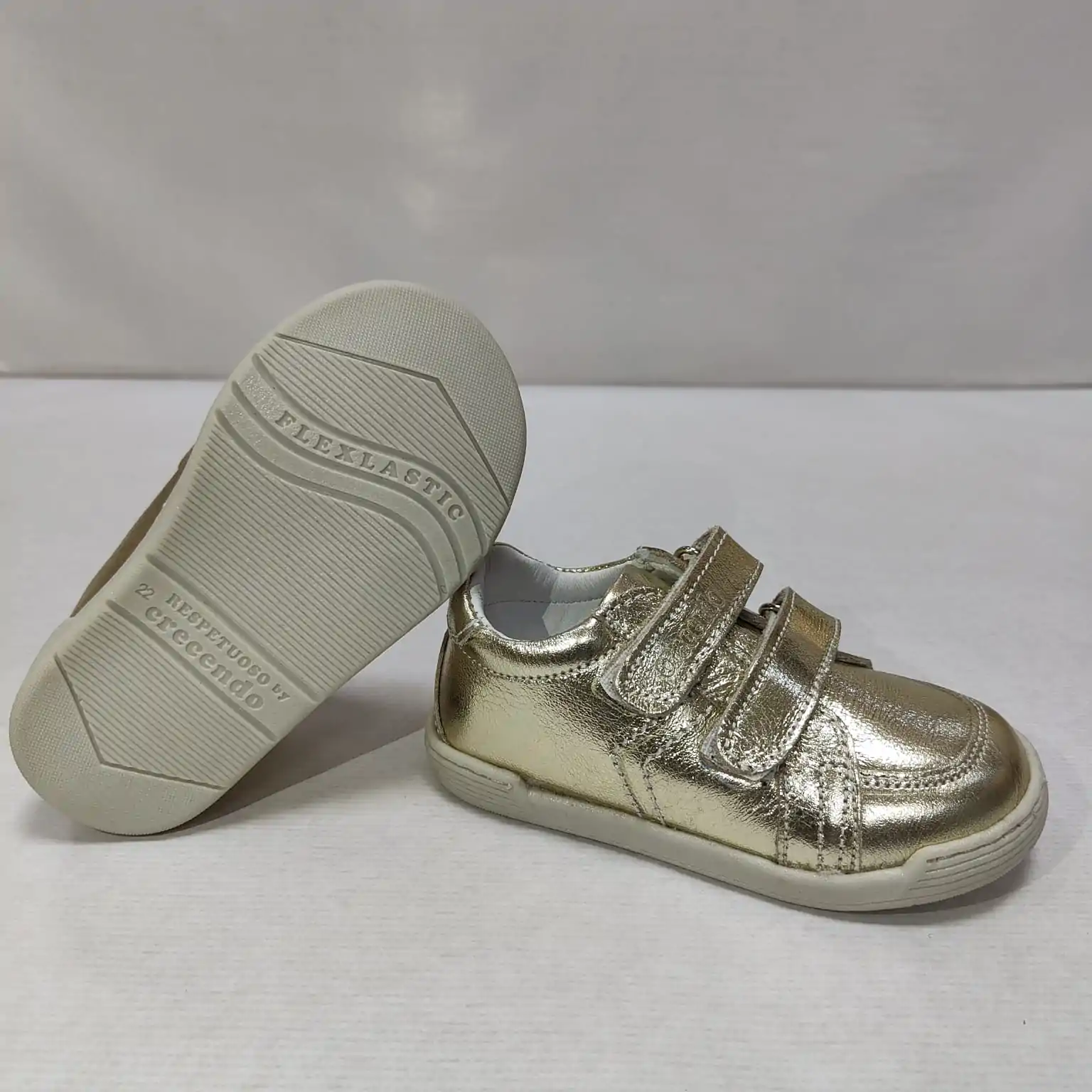 Zapato respetuoso infantil Crescendo en piel dorada, vista lateral mostrando su diseño brillante con doble cierre de velcro y suela flexible Flexlastic para mayor comodidad.