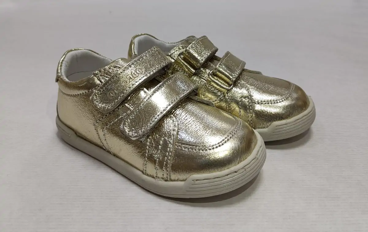 Zapatos respetuosos Crescendo en piel dorada, diseño con doble velcro y acabados metálicos, ideales para niños. Ofrecen flexibilidad y comodidad para el uso diario.