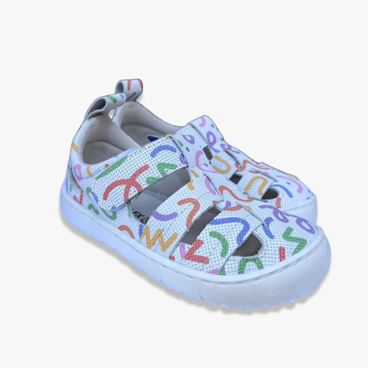 Sandalias respetuosas niño Coqueflex Verea Blanco en vista en ángulo, mostrando ambos zapatos con diseño colorido, corte en tiras y suela blanca antideslizante.